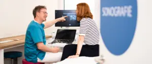 Dr. Rüdiger Soukup zeigt Patientin Ultraschall
