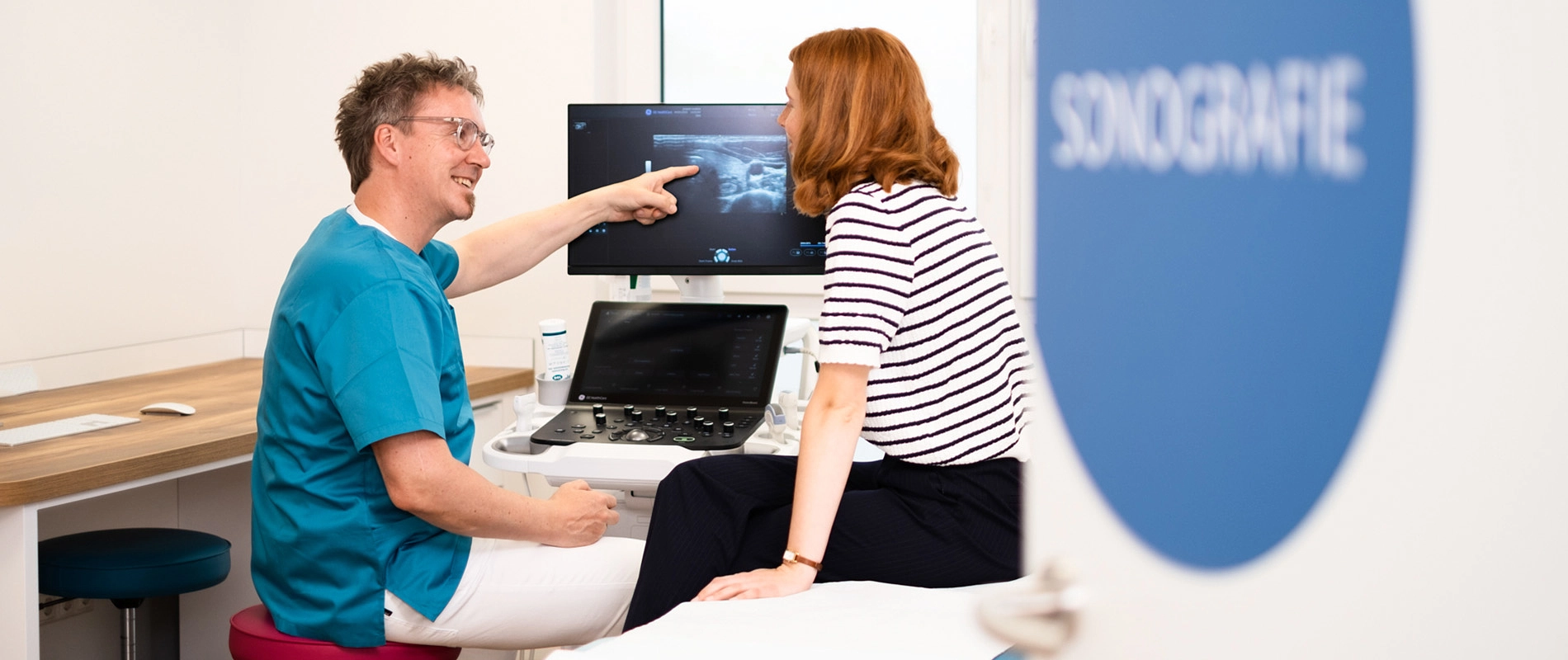 Dr. Rüdiger Soukup zeigt Patientin Ultraschall